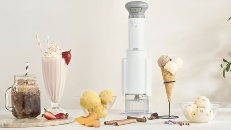 A tall white Cuisinart ice cream maker surrounded by milkshakes, slishes, and ice cream. 