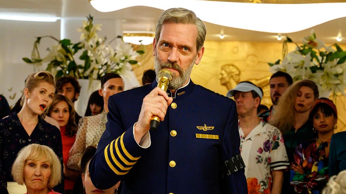 Avenue 5 season 2 star Hugh Laurie holding a microphone in front of a crowd