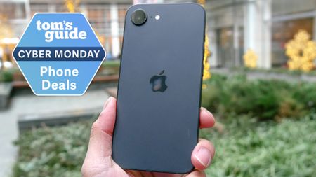 iPhone 16e held in the hand with Cyber Monday badge nearby.