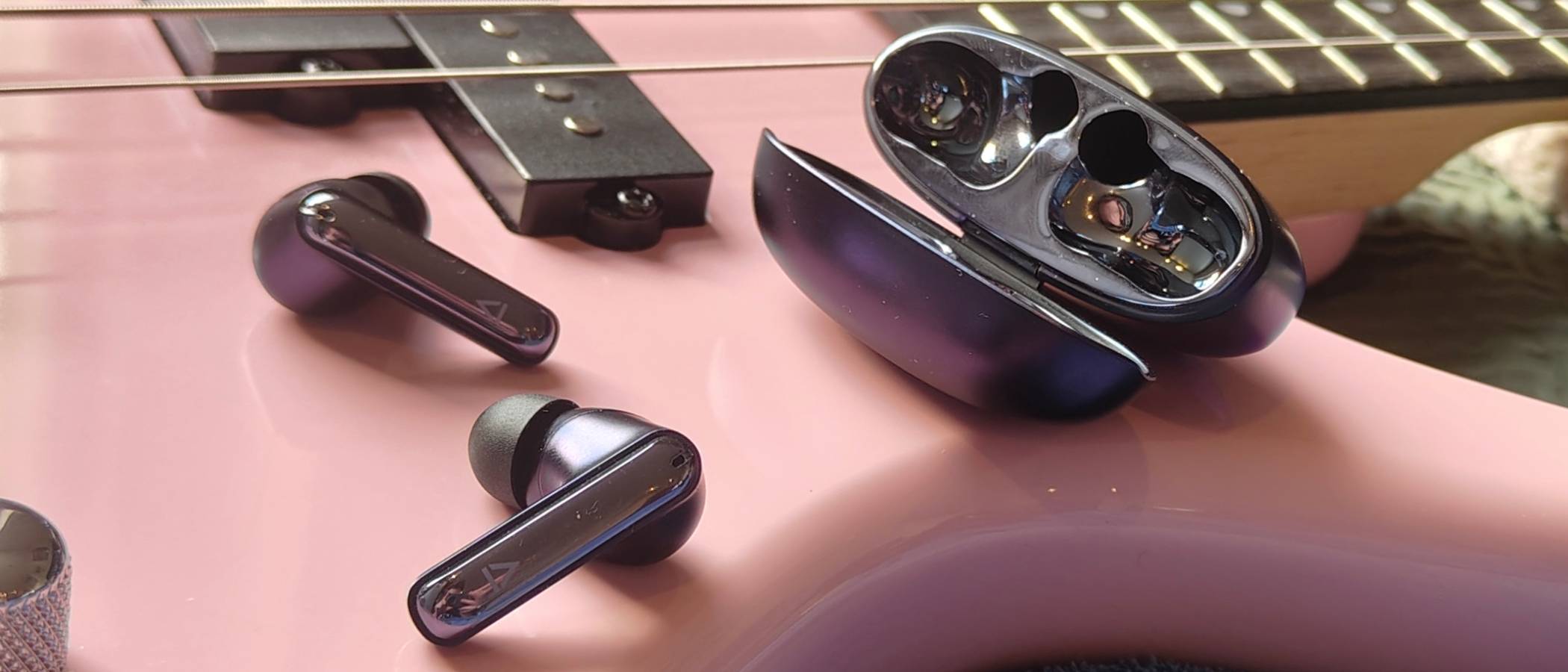 The Creative Aurvana Ace 3 buds and case on a pink bass guitar.