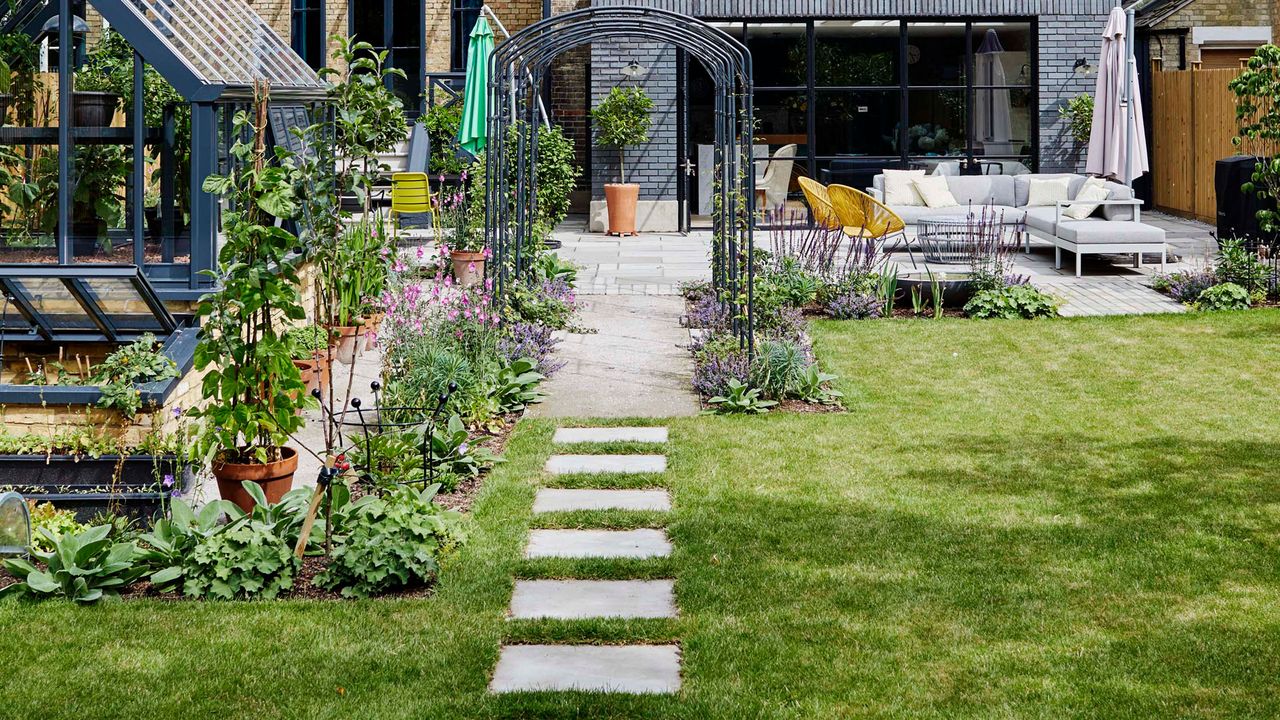 Exterior of home with lawn, patio area, stepping stones and greenhouse