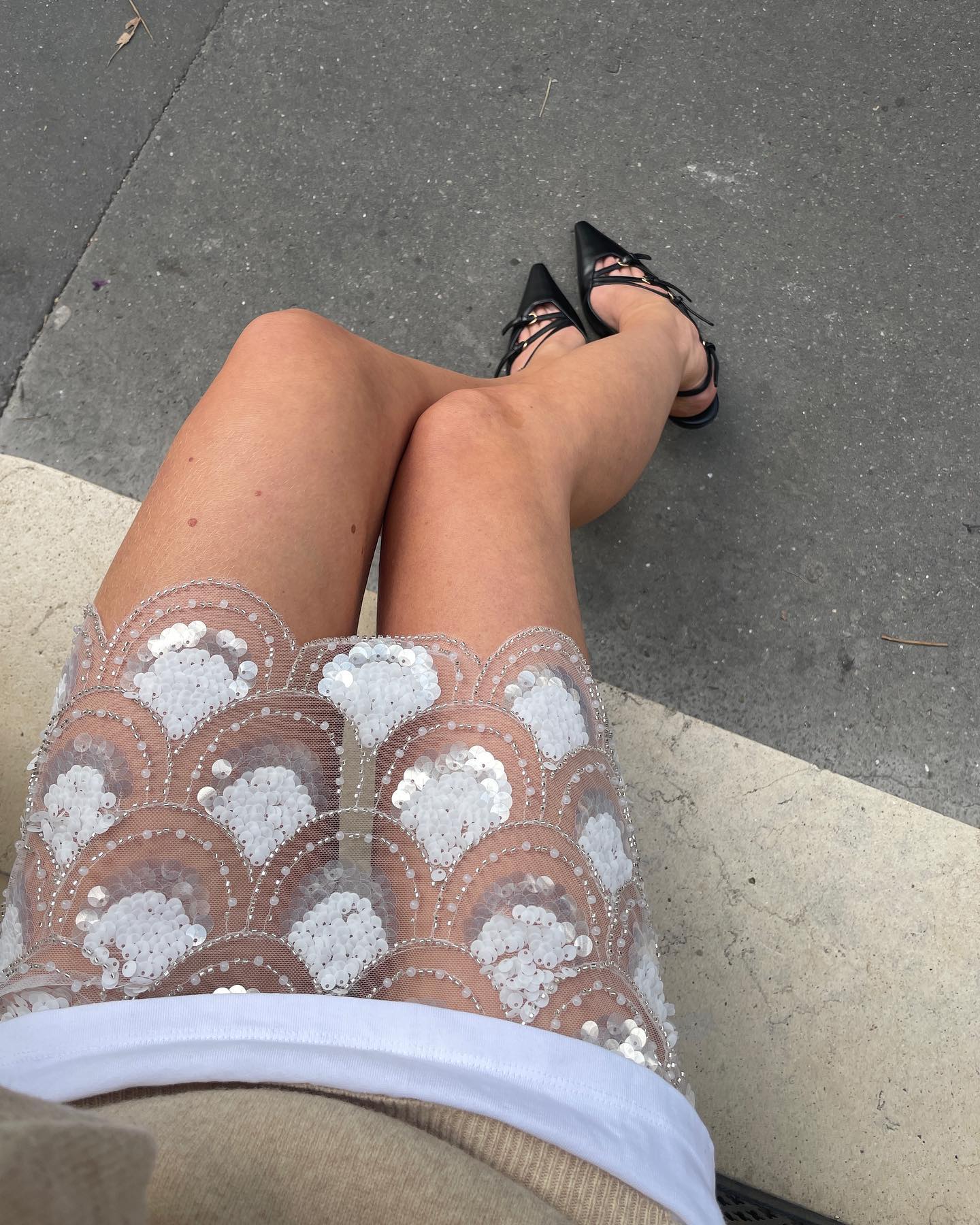 Jeanette Madsen sits and poses in an embellished sheer skirt