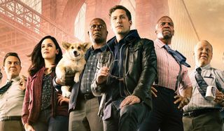 The cast of Brooklyn Nine-Nine stands triumphantly under the Brooklyn Bridge.