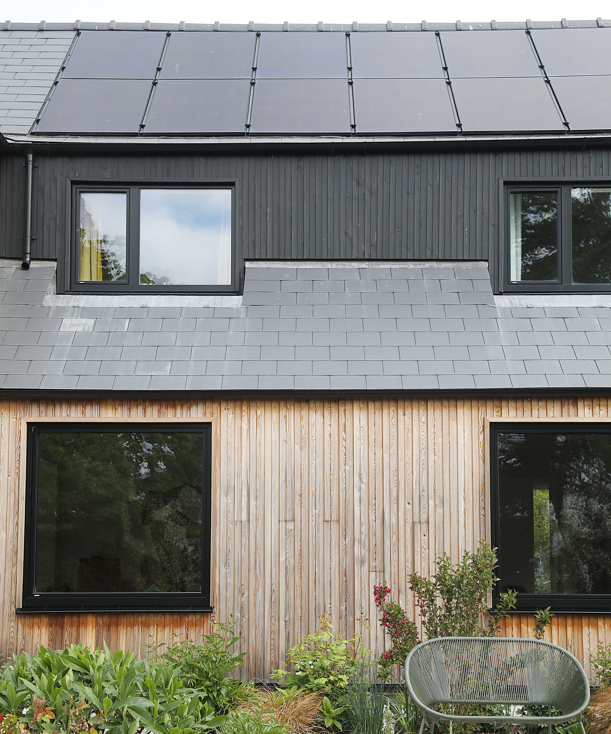 timber clad house with a bank of solar PV panels on the roof