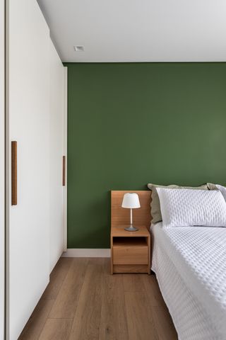 A bedroom with dark green walls and white bedding