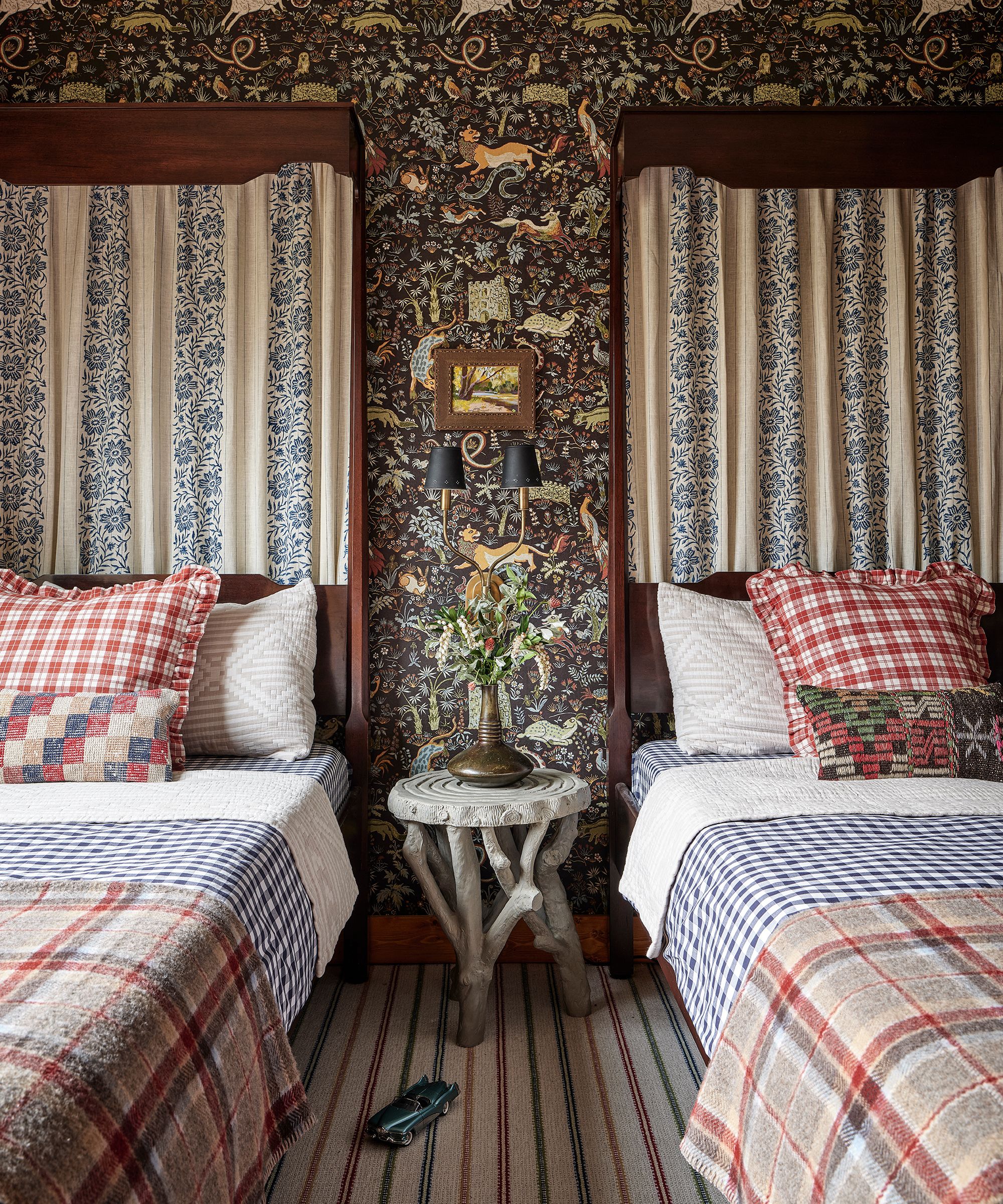 a twin bedroom with house of hackney wallpaper and antique canopy beds with gingham sheets and striped carpet