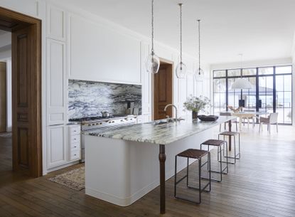 A kitchen with wooden flooring and white island and walls 