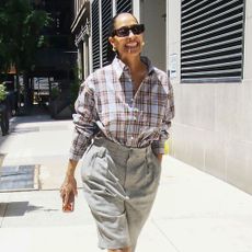 Tracee Ellis Ross wears Bermuda shorts with brown peep-toe mules and a checked shirt.