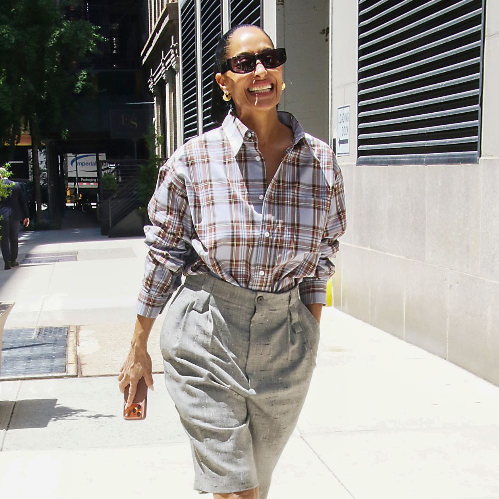 Tracee Ellis Ross wears Bermuda shorts with brown peep-toe mules and a checked shirt.