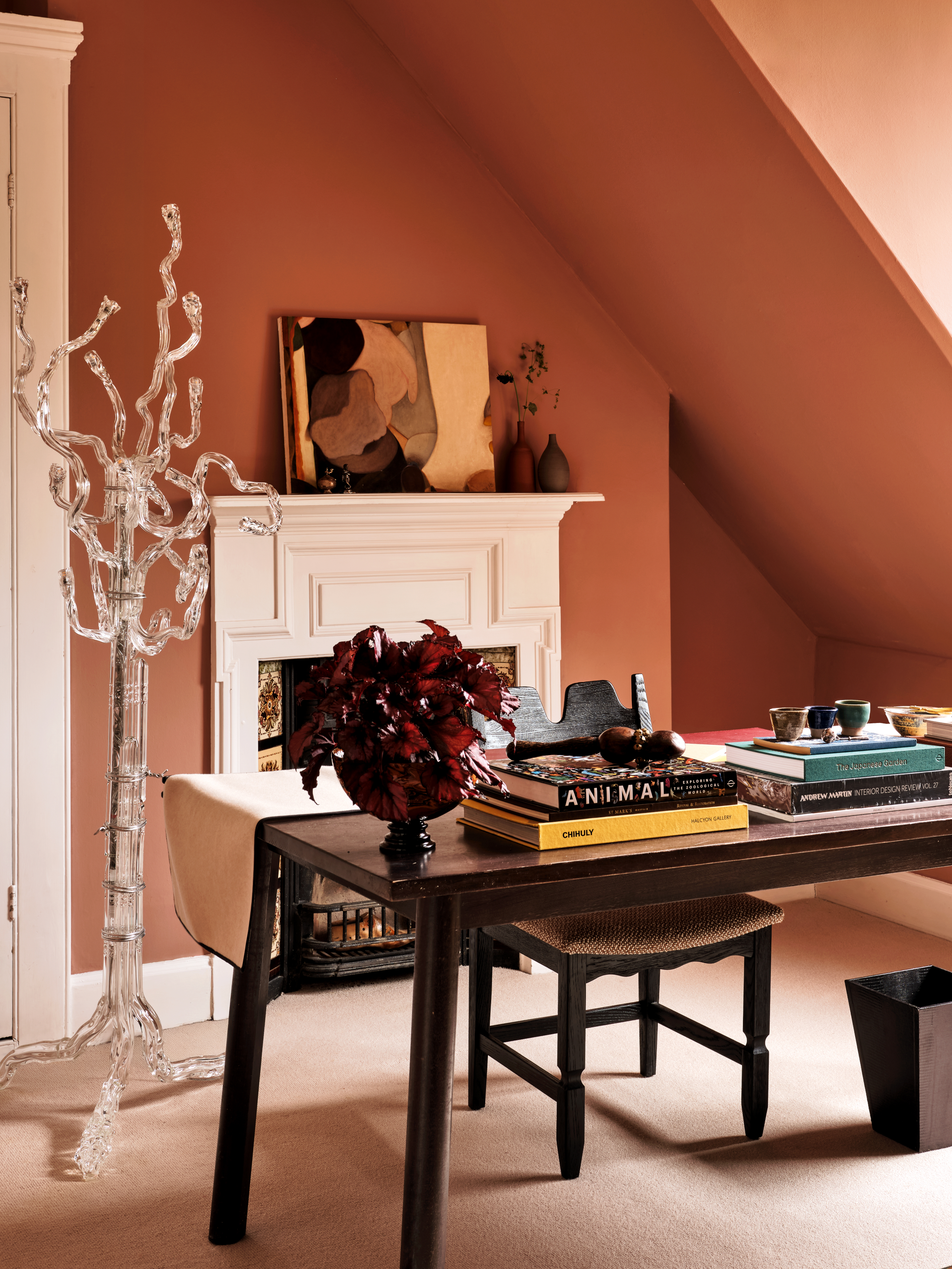 Terracotta-colored home office with wooden desk and sculptural glass floor lamp