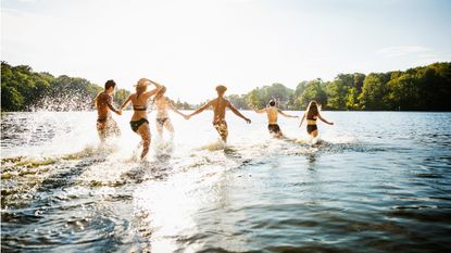 Several people run into a lake on summer vacation.