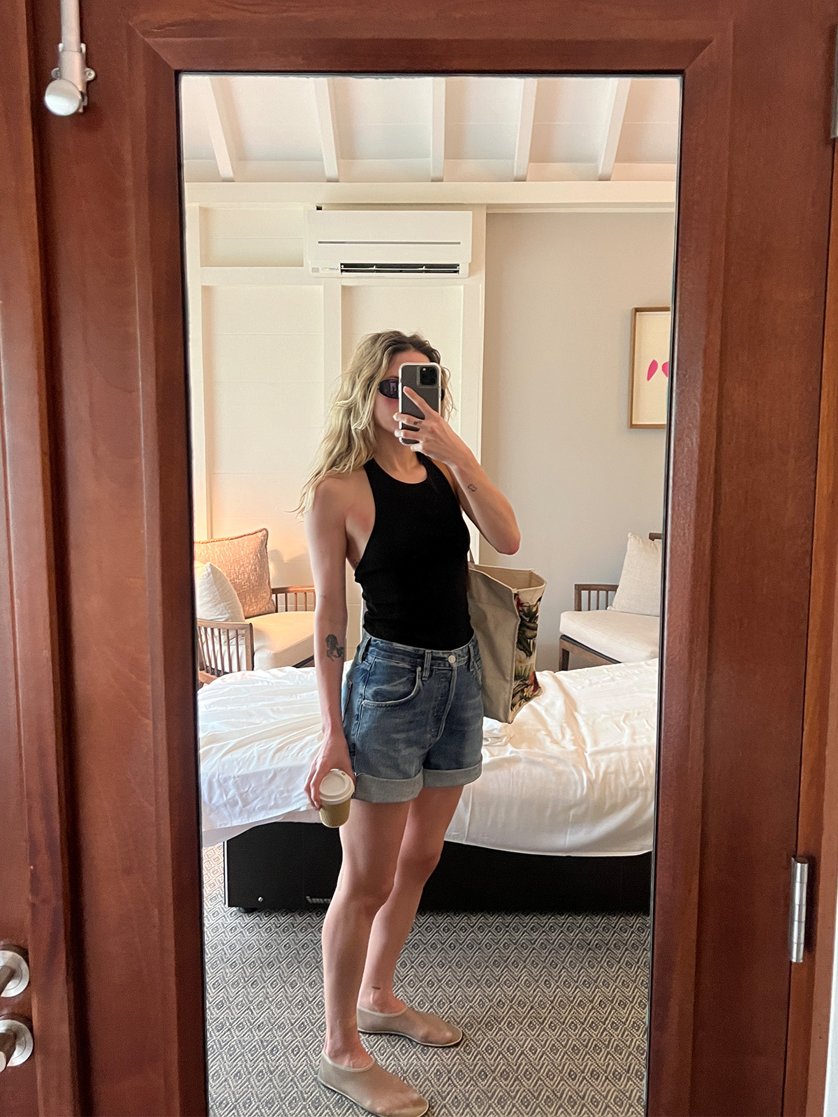 Eliza Huber wearing a black halter top, jean shorts, and The Row mesh flats.