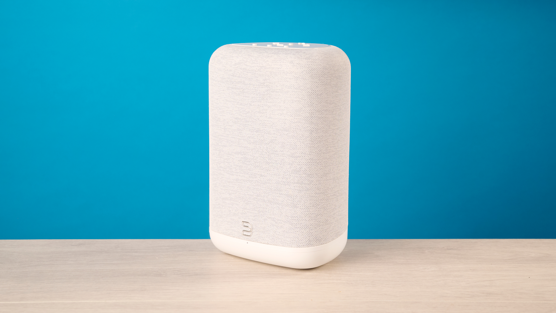the bluesound pulse flex wi-fi speaker in pale gray photographed against the blue tom's guide background