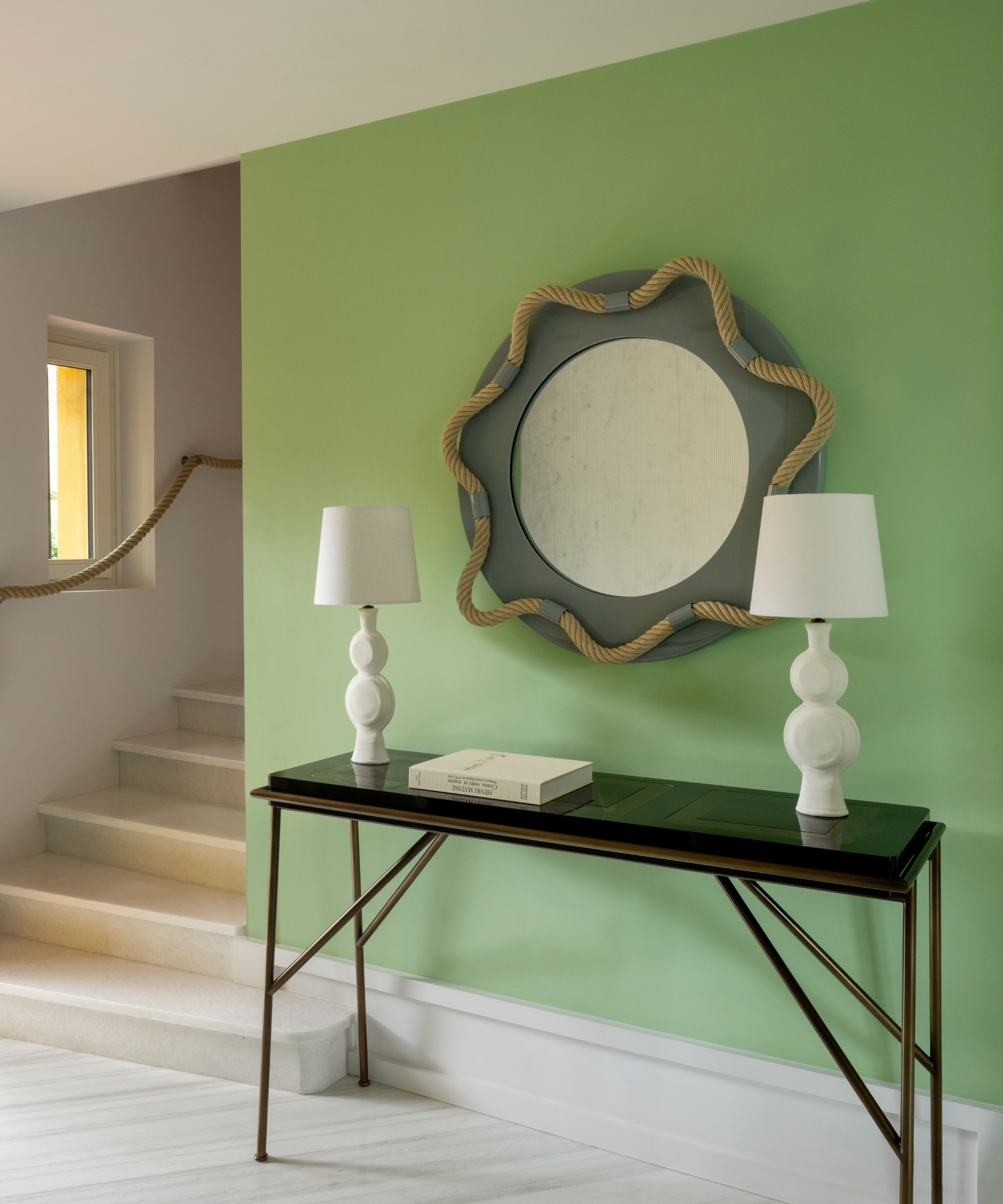 Pea green hallway wall holding accent mirror framed uniquely with rope