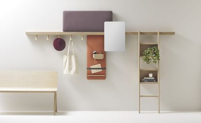 A wooden bench below a wall shelf with clothing hangers under it and laddered shelves on the right of it.