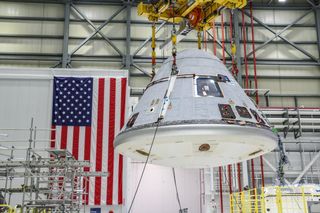 The fully assembled Starliner spacecraft being prepared to fly Boeing’s Orbital Flight Test-2 is lifted inside the Starliner production factory at Kennedy Space Center in Florida, on Jan. 13, 2021.