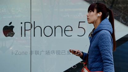 A Chinese woman listens to her iPhone outside an Apple reseller store in Beijing on April 2, 2013. Apple chief executive Tim Cook has apologised to Chinese consumers after the US technology g