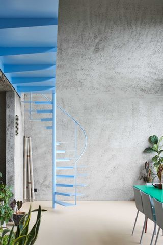 a brutalist apartment with a pastel blue staircase