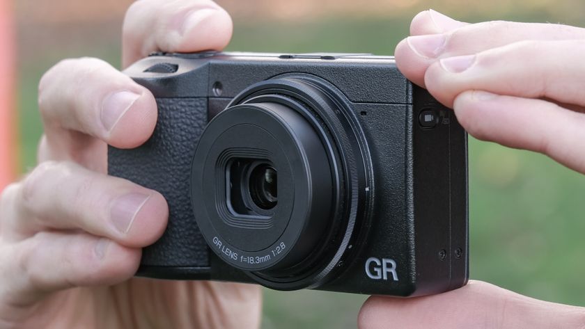 Ricoh GR IV compact camera held in a pair of hands