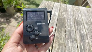 Majority Petersfield Go DAB radio held in hand with garden and wooden table in background