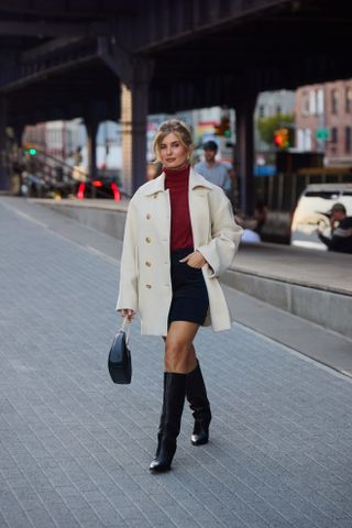 woman wearing turtleneck, skirt, boots, and handbag