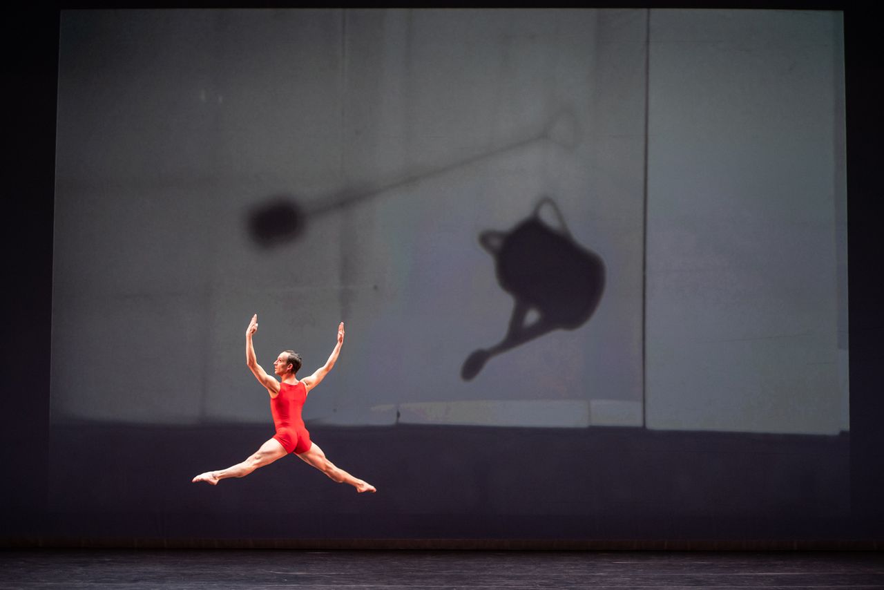 Man doing a solo on stage with a red unitard on