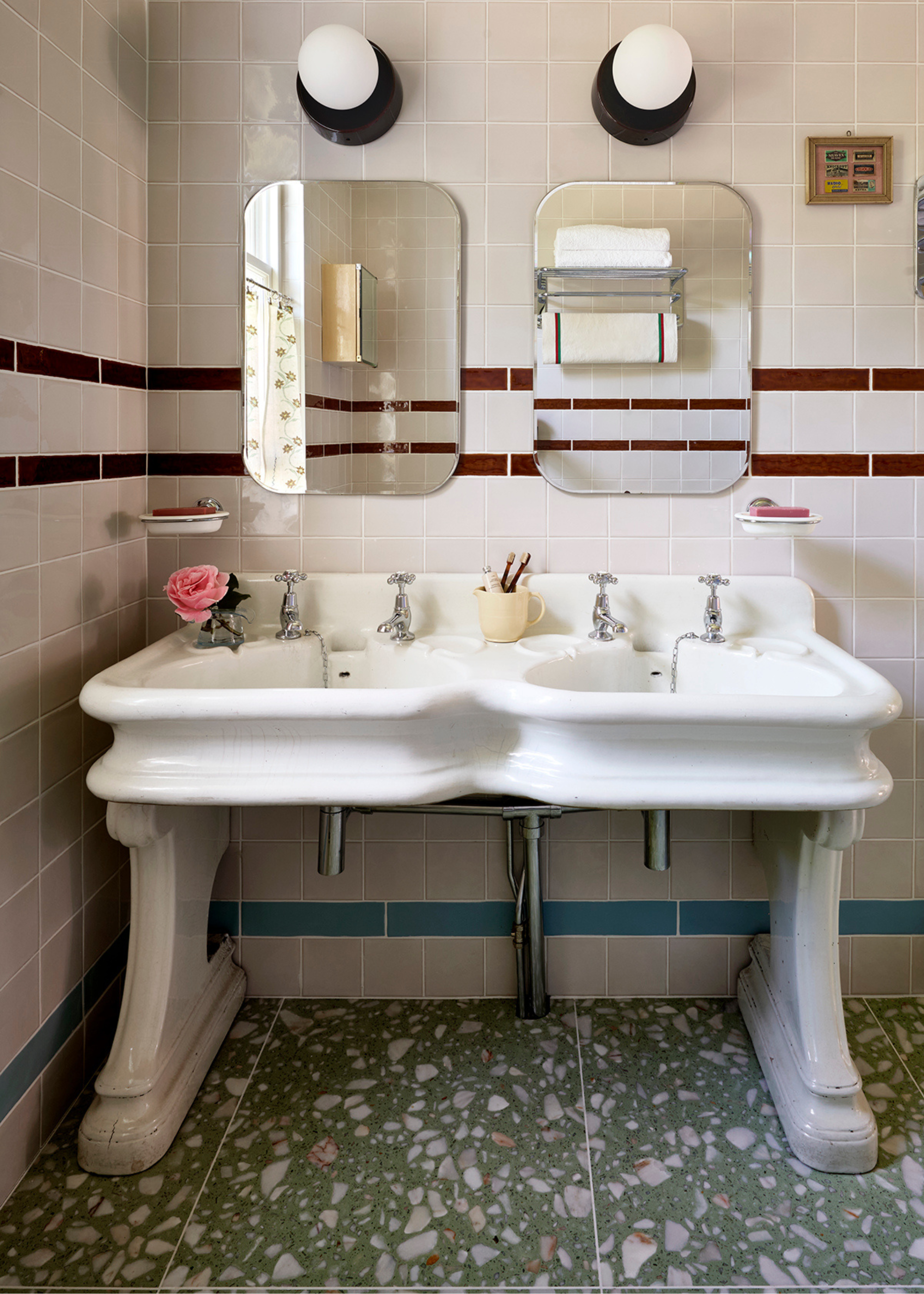 double vanity sink with two mirrors and lights in a tiled bathroom with green terrazzo floors