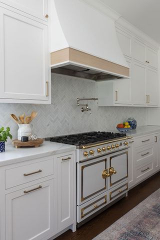 A kitchen with white cabinets and gold hardware