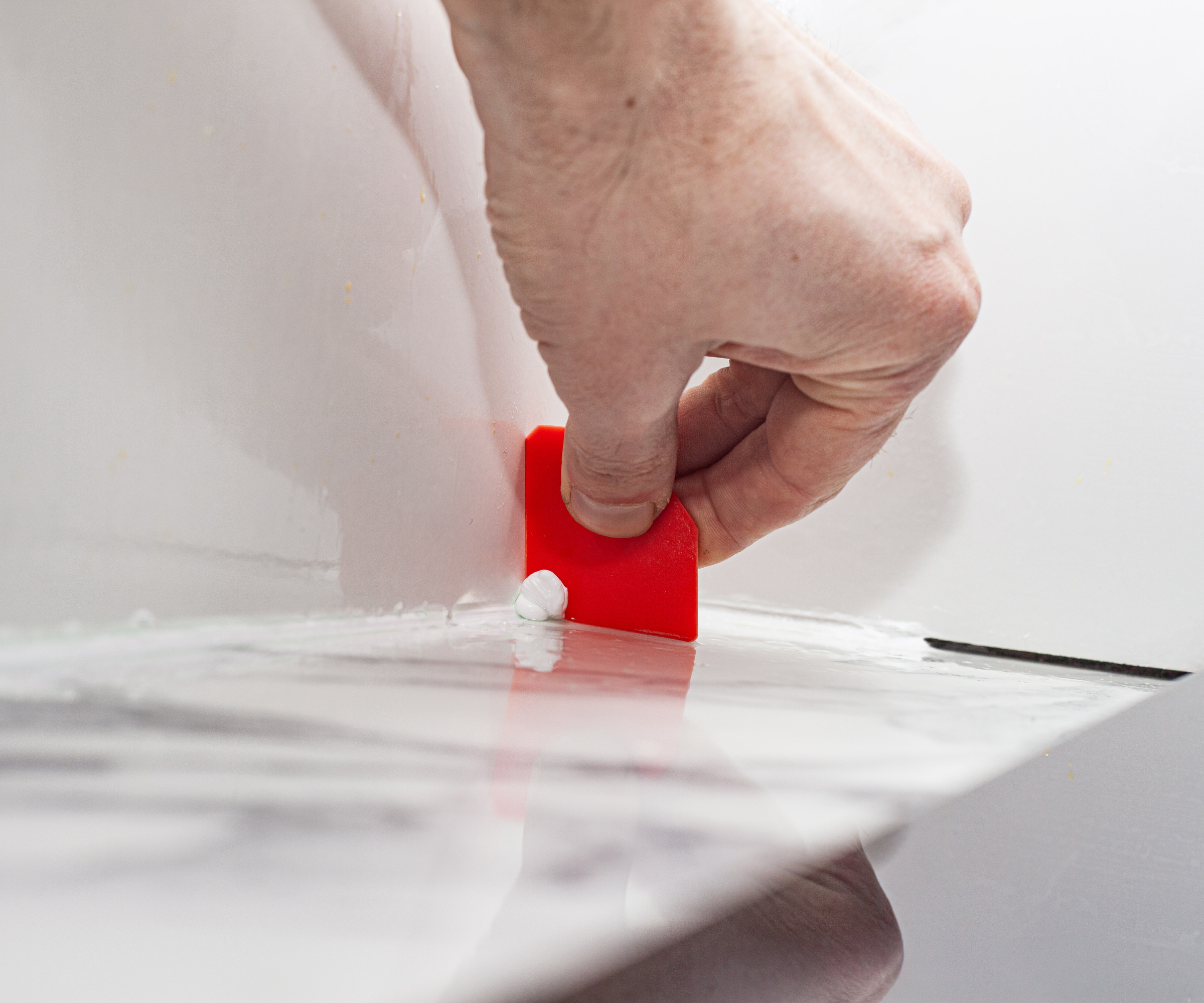 hand applying sealant to edge of tiled areas in bathroom