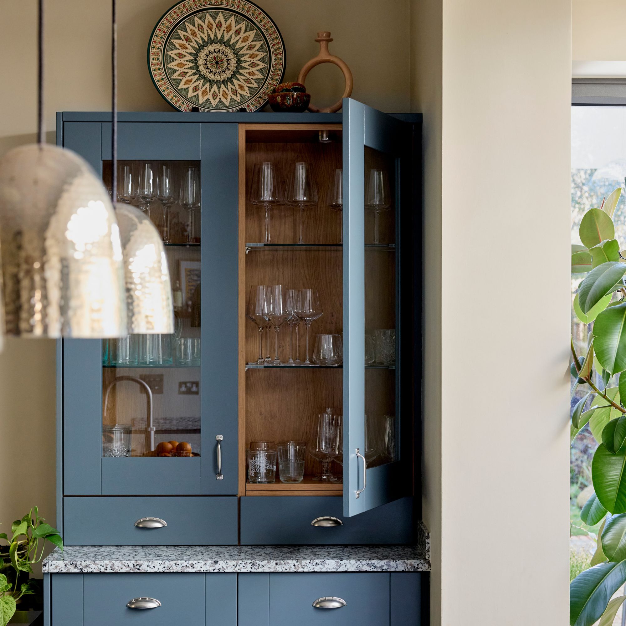 Blue painted drinks cabinet with shelves full of glasses