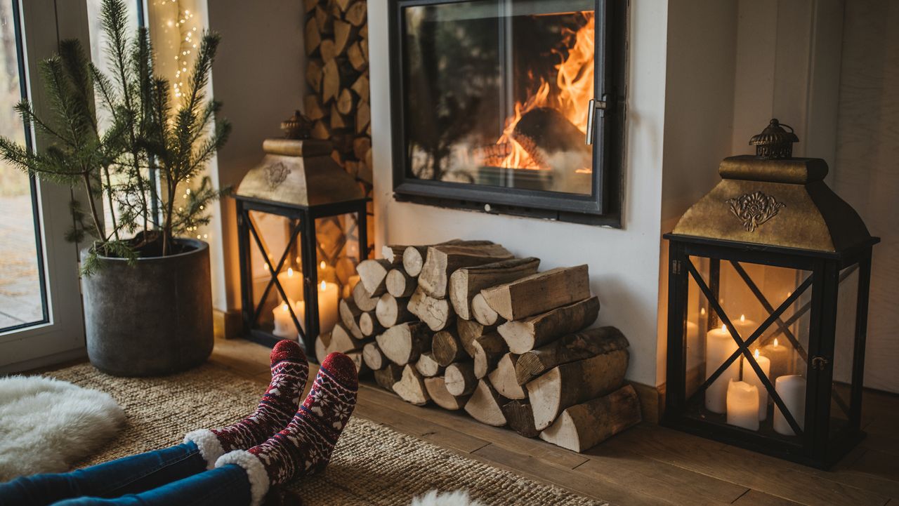 cottagecore christmas decor ideas in a living room with woman&#039;s feet in red socks in front of fire place and a fireplace burning and rustic accents