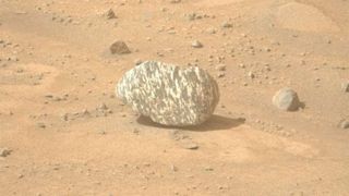 Image of a striped rock captured by NASA&#039;s Perseverance rover on Mars. The rock lies on dusty, sandy ground.