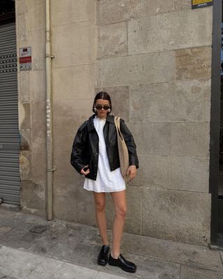 @maryljean wearing a leather jacket, loafers and a white mini dress