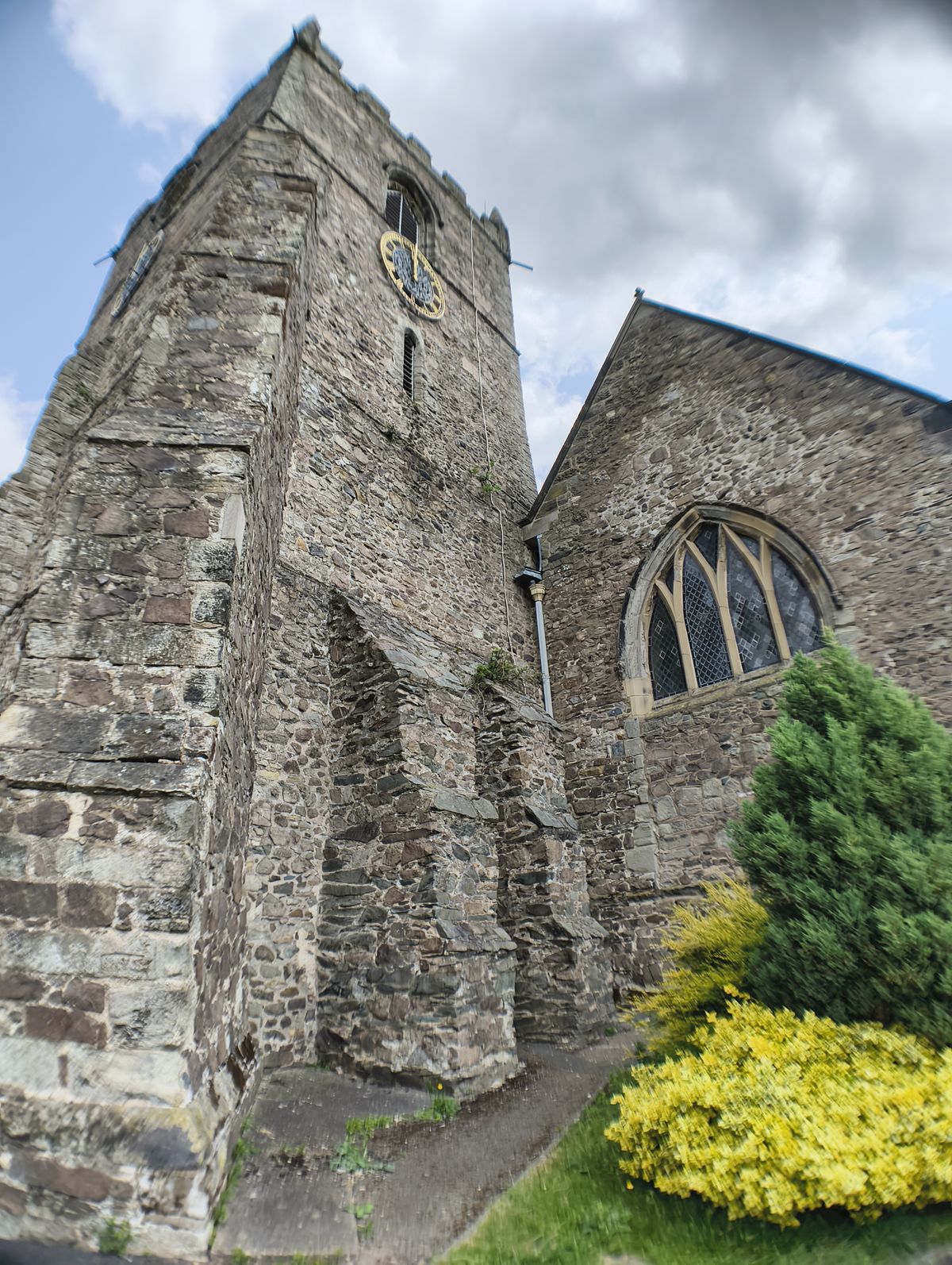 Stone church tower next to some green bushes