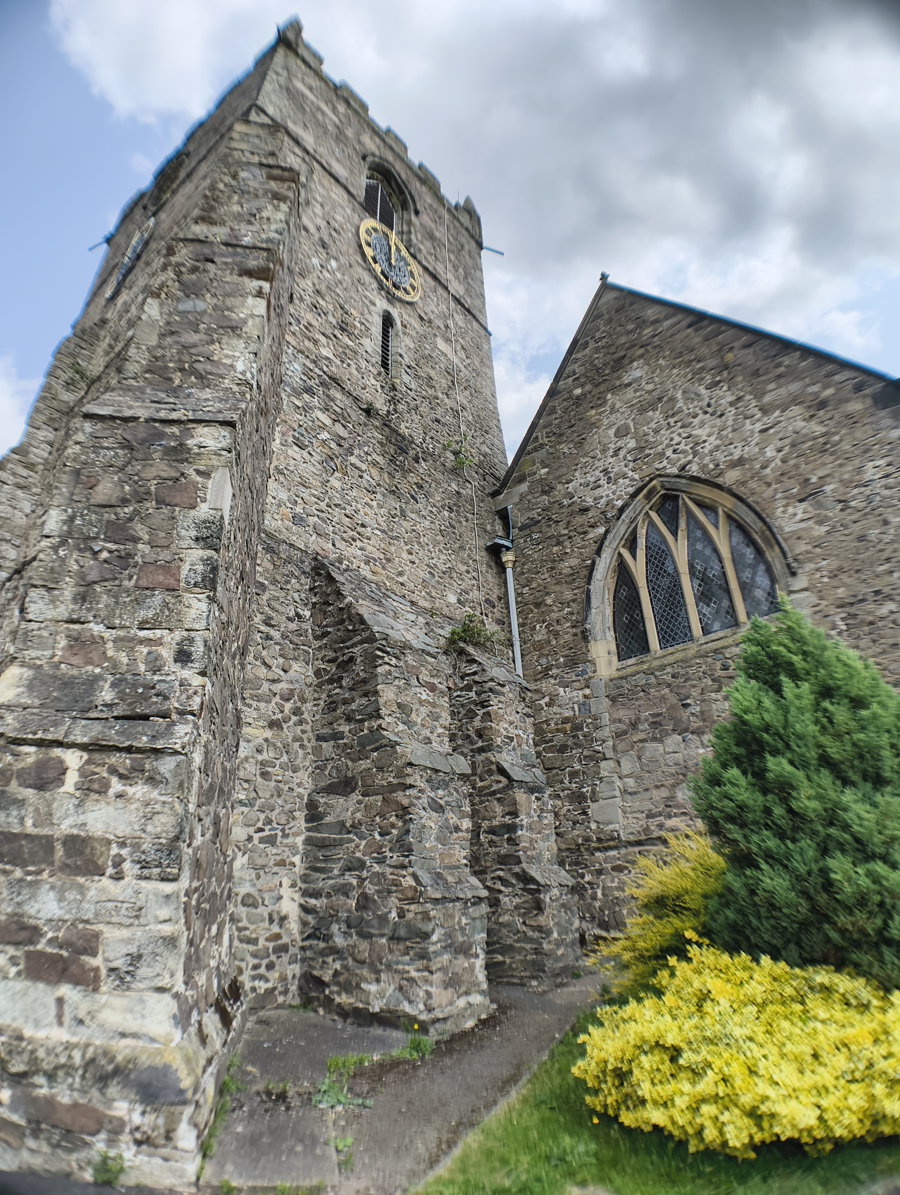 Stone church tower next to some green bushes