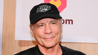 Bruce Dickinson smiling in a black baseball cap