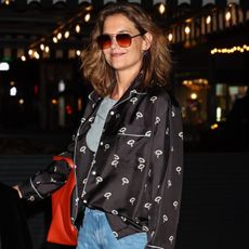 Katie holmes wears jeans and a black patterned silk blouse.