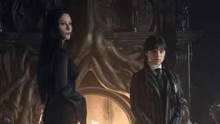 Morticia and Wednesday standing in front of fireplace in Wednesday Season 2