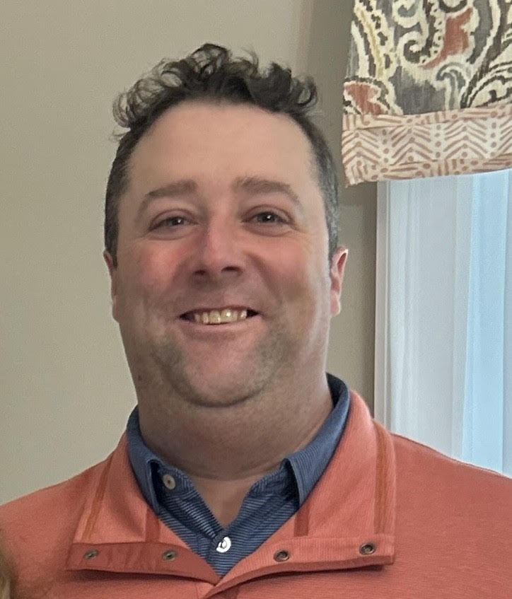 Headshot of man in orange shirt