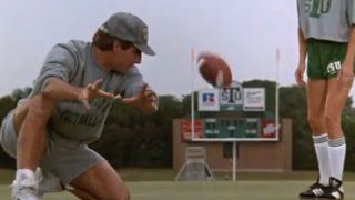 Scott Bakula on one knee looking back at a football flying through the air in Necessary Roughness