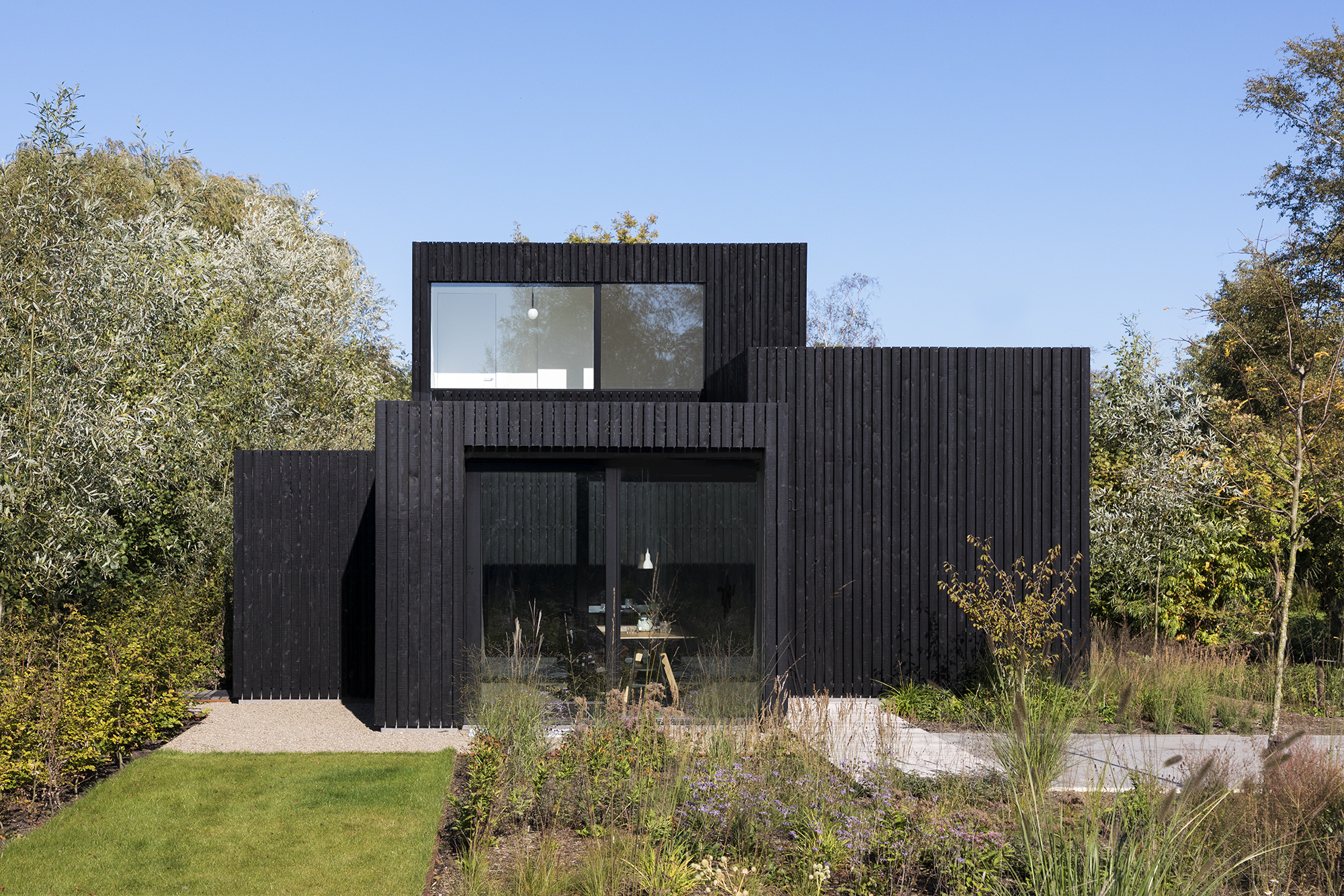 Exterior of the black holiday home with landscaping