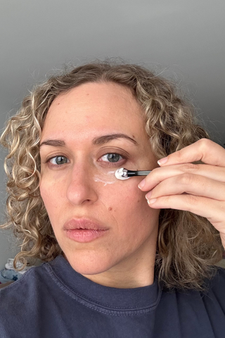 woman applies la mer eye cream to her face