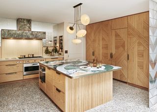 Sleek oak style kitchen cabinets with striking marble place on top of the extended island. Additional storage added into the island making it multifunctional. A large pendant light sits above the island too.