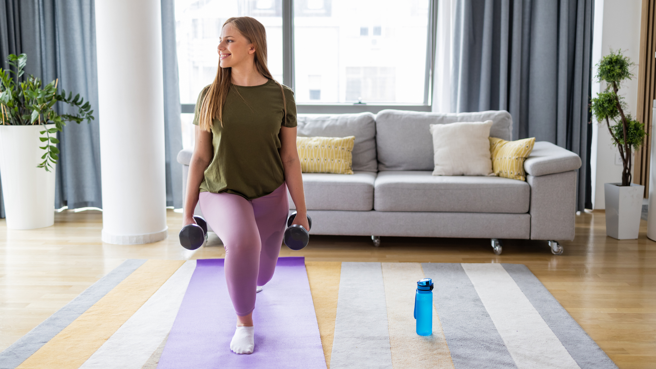 Woman exercising with dumbbells in front of a couch