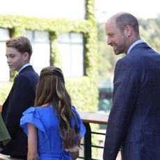 Prince George walking with Princess Charlotte and Princess Kate across a bridge