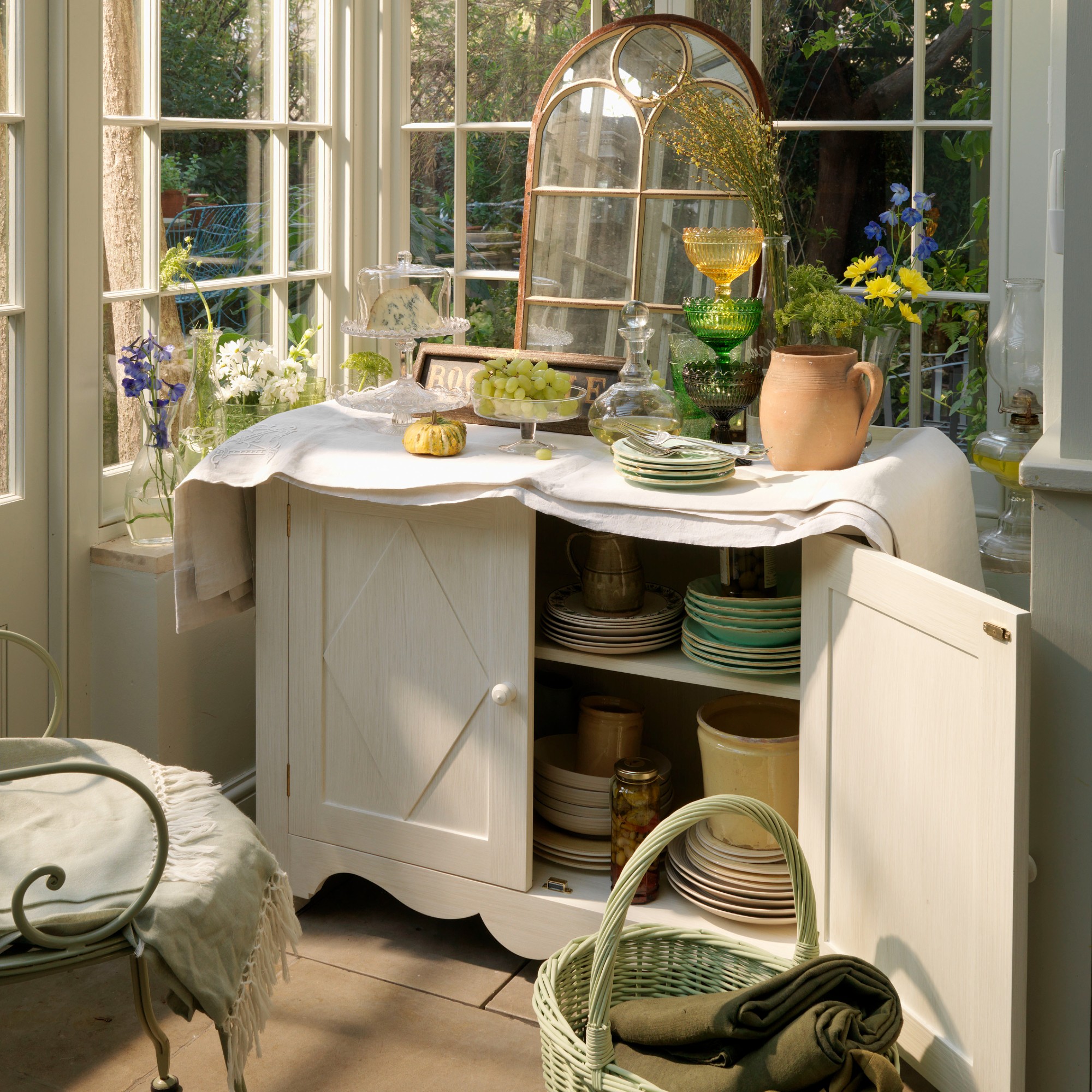 A white conservatory with a vintage cabinet used for tableware storage