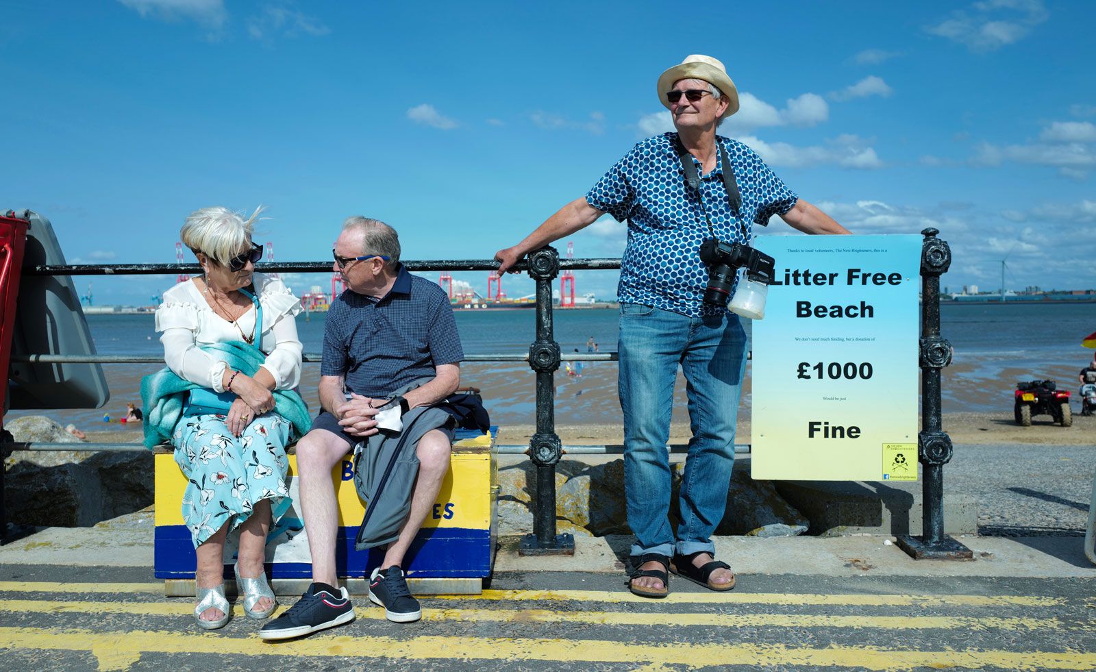 Martin Parr on British seafront, beside seated couple