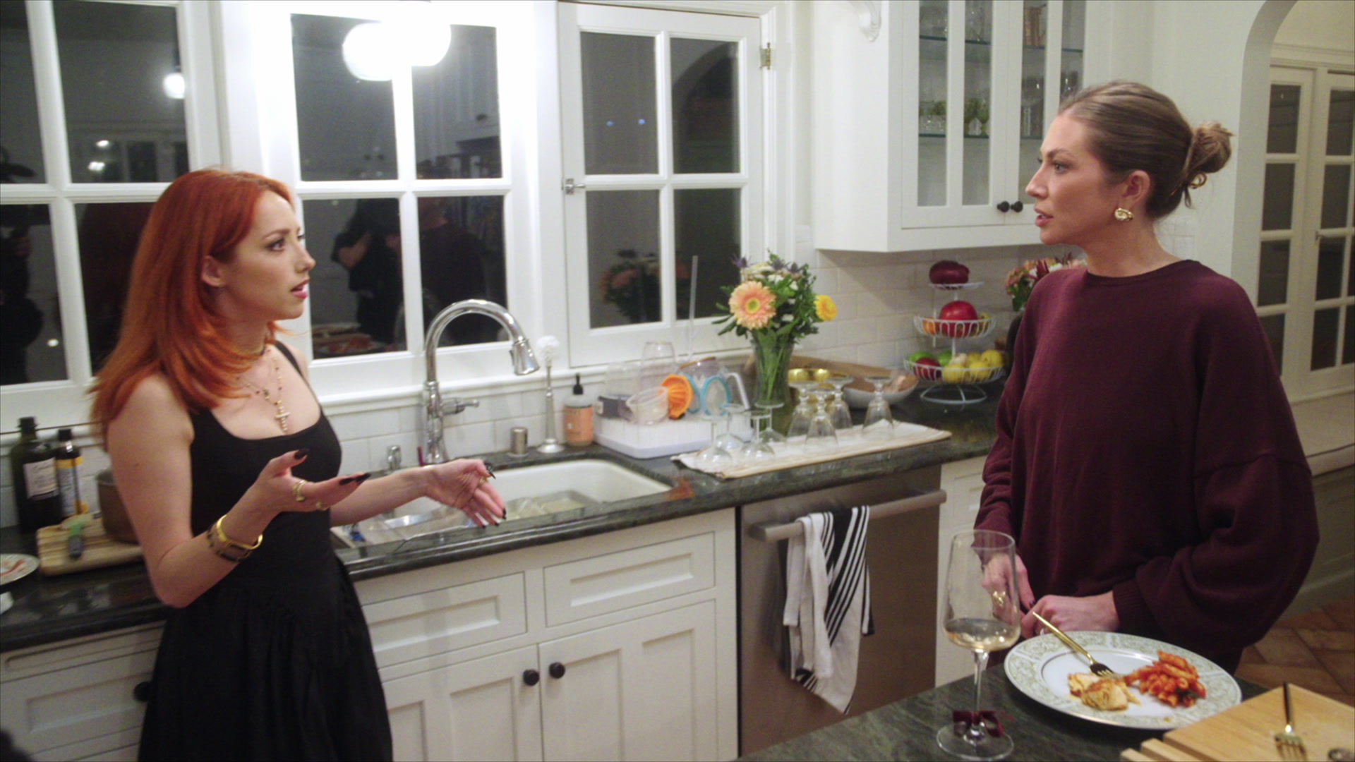 GEORGIANNA AUBIN and STASSI SCHROEDER CLARK have a conversation in a kitchen at night in a still from house of stassi