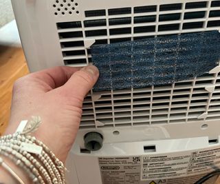hand putting blue filter in place on back of dehumidifier