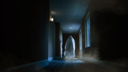 An image showing a ghostly figure walking down a hotel hallway at night